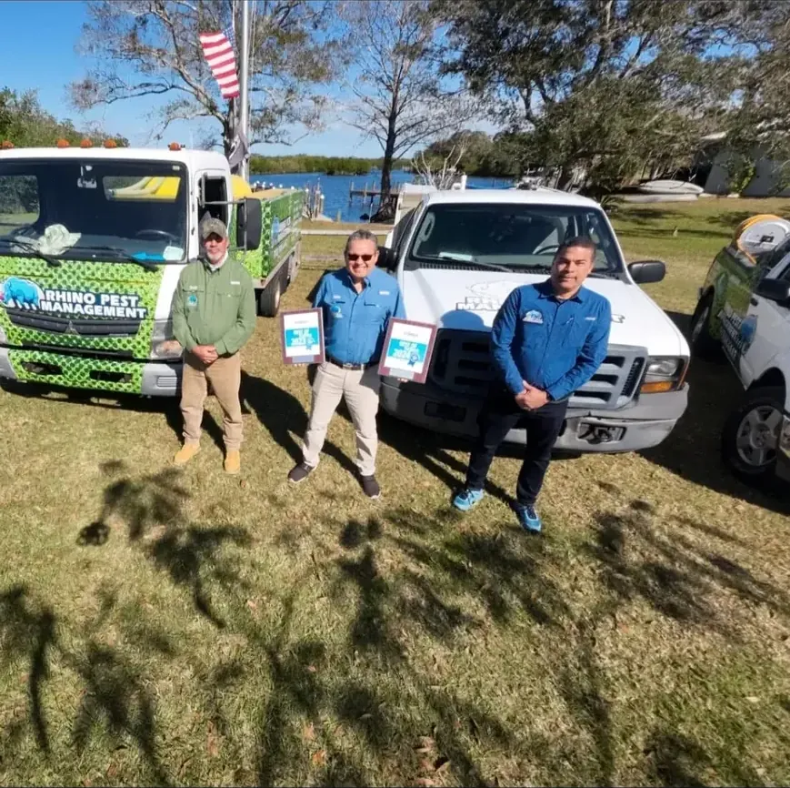 The Rhino Pest Management team holding their Best of Florida award plaques in front of their service trucks on Florida's Treasure Coast